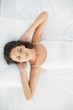 © lightwavemedia - Attractive casual brunette in white pajamas sleeping on her bed