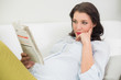 © lightwavemedia - Thinking pregnant brown haired woman reading a newspaper