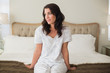 © lightwavemedia - Pensive pretty brown hair woman sitting on a bed