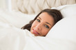 © lightwavemedia - Smiling pretty brown haired woman relaxing in her bed