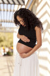 A pregnant woman looks down at her protruding belly.