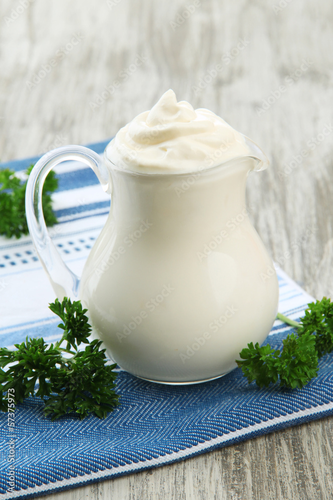 Sour cream in pitcher on table close-up