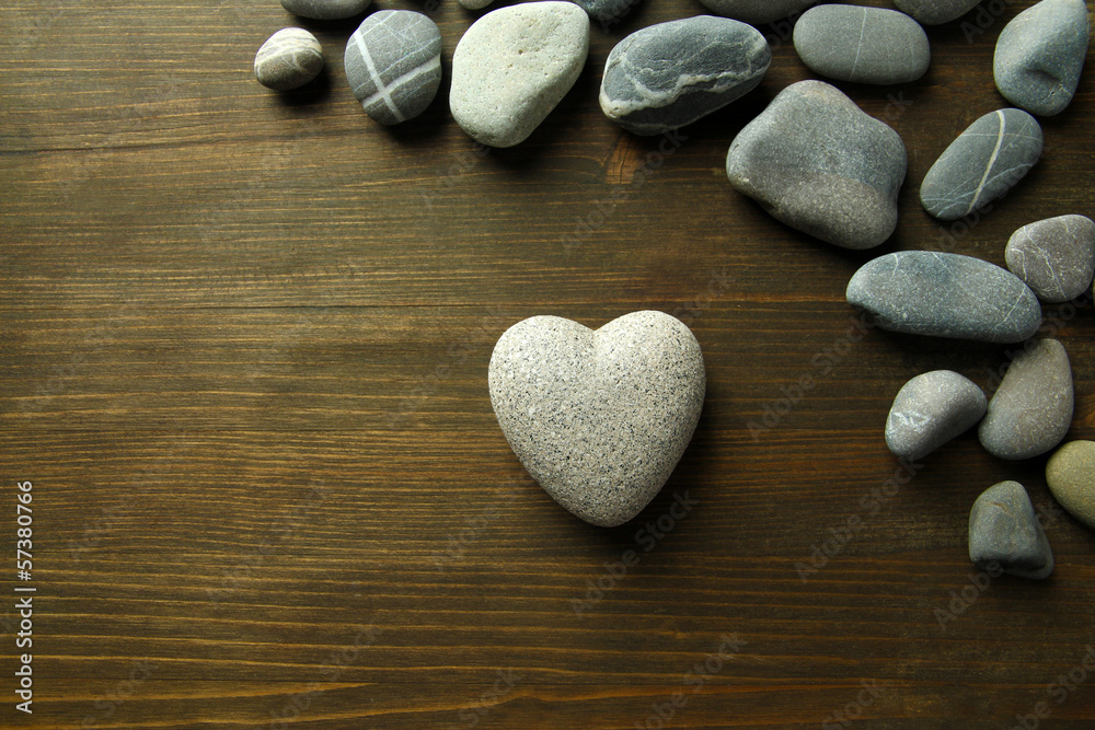 Grey stone in shape of heart, on wooden background