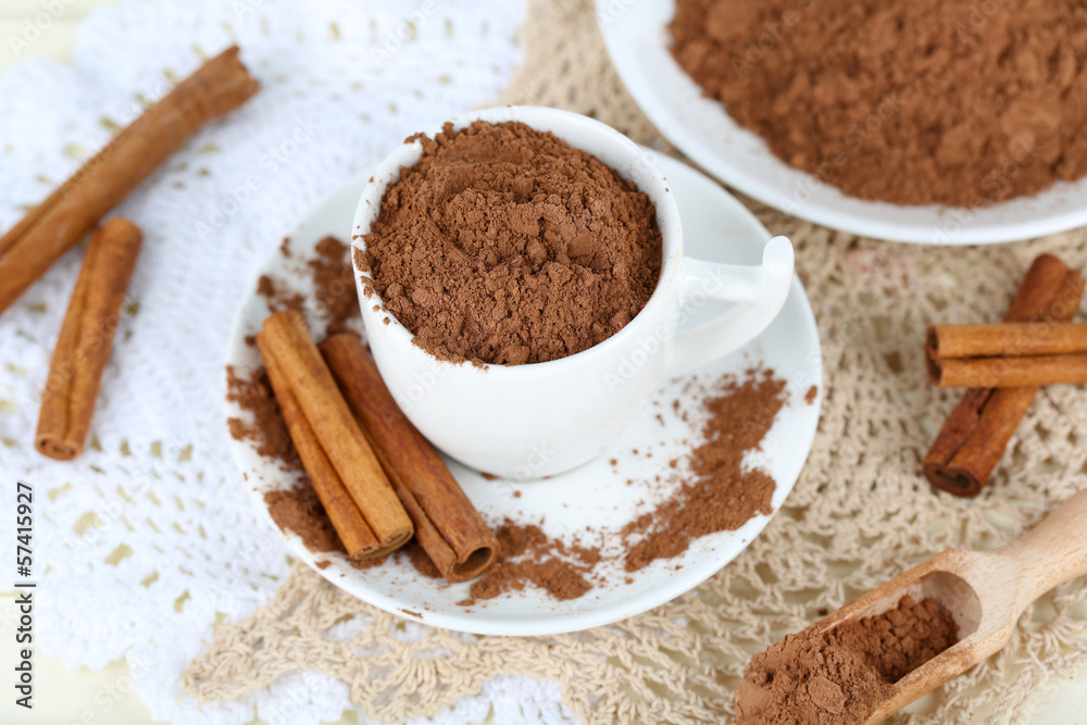 Cocoa powder in cup on napkin on light background