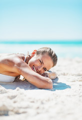 Poster - Portrait of smiling woman in swimsuit laying on sandy beach