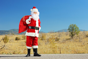 Poster - Full length portrait of a Santa claus with bag full of presents