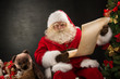 © Milles Studio - Portrait of happy Santa Claus reading Christmas letter or wish l