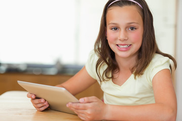 Poster - Girl sitting at kitchen table with tablet