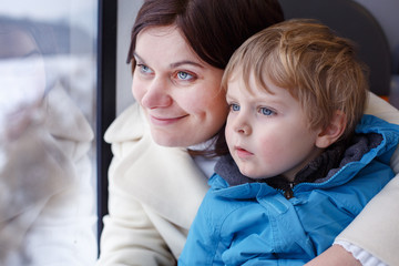 Mother and toddler son looking out train window outside