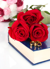 Wall Mural - Wedding rings with roses on bible isolated on white