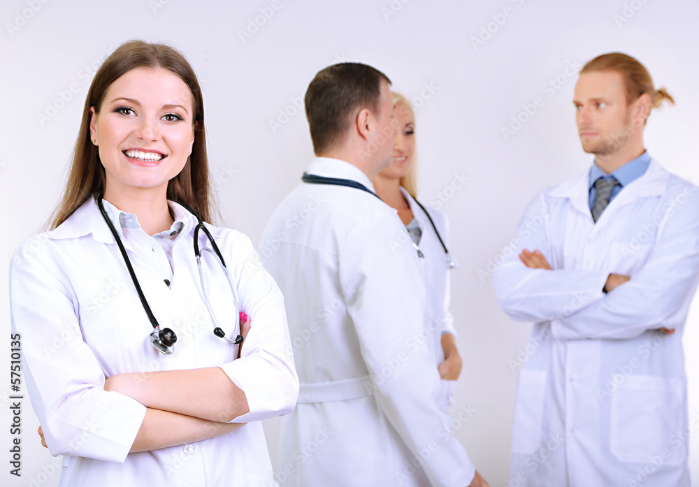 Doctor standing in front of coworkers on grey background