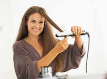 Happy Young Woman Straightening Hair With Straightener