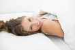 © lightwavemedia - Cheerful attractive woman lying under the cover on her bed
