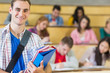 © WavebreakmediaMicro - Smiling male with students sitting at lecture hall