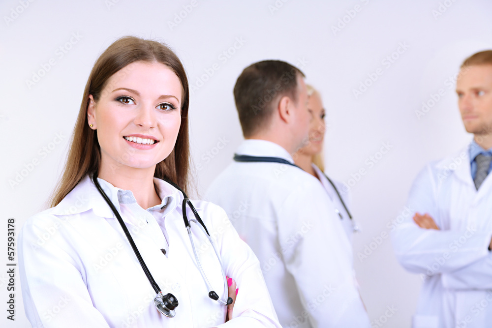 Doctor standing in front of coworkers on grey background