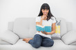 © lightwavemedia - Peaceful content woman reading a book sitting on couch