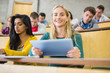 © WavebreakmediaMicro - Female holding tablet PC with students at lecture hall