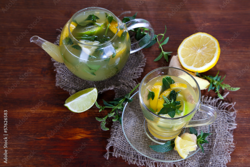 Kettle and cup of tea with ginger on sackcloth on wooden table