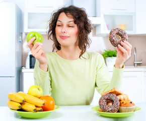 Wall Mural - Dieting concept. Young Woman choosing between Fruits and Sweets