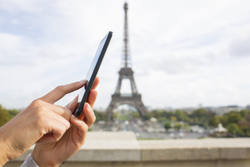 Wall Mural - Woman in Paris using her cell phone in front of Eiffel Tower