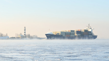 cargo container ship sailing in still frozen winter sea