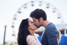 romantic couple kissing in front of santa monica ferris wheel