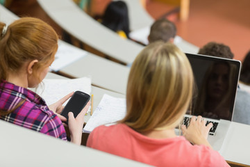 Females using laptop and cellphone in the lecture hall