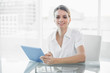 © lightwavemedia - Gleeful smiling businesswoman working with her tablet looking at