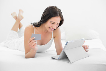 Casual young woman doing online shopping in bed