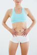 © lightwavemedia - Mid section of a fit woman in sportswear with hands on belly