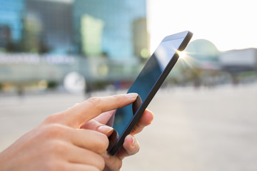 Businesswoman sending messages with her mobile phone, building