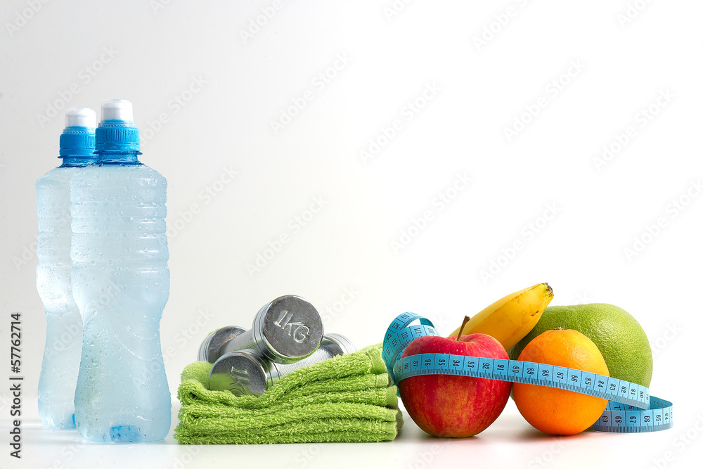 Obraz Hantle fitness z owocami i wodą na białym tle. fototapeta, plakat