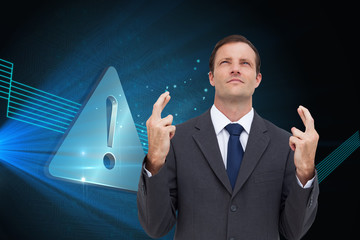 Composite image of serious businessman with fingers crossed is l