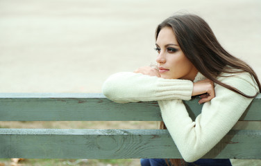 Wall Mural - Young lonely woman on bench in park