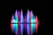 The Dancing Fountain Show Has A Reflection On The Water Surface. The Background Is Black.