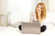 © Drobot Dean - Young beautiful woman sitting on the bed with laptop at home