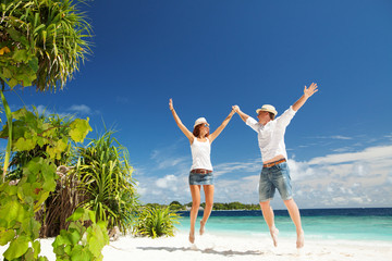 Happy couple jumping on the tropical beach