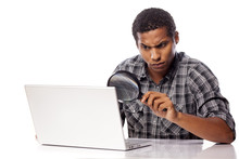 African Man Looking Through A Magnifying Glass On His Laptop