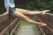 Stretched Legs Of Woman Sitting On Bridge