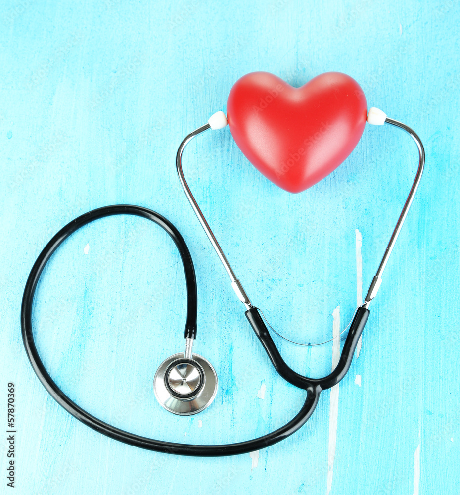 Stethoscope and heart on wooden table close-up