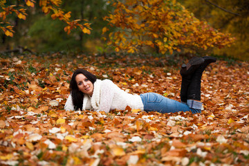 Beautiful woman is lying in a park in autumn