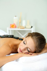 Canvas Print - Beautiful young woman having stone massage in spa salon