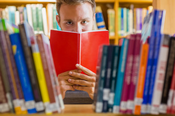 Poster - Male student holding book in front of his face in the library
