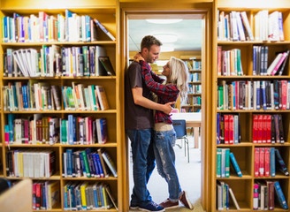 Poster - Romantic couple embracing by bookshelves in library