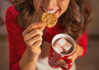 Closeup on happy housewife drinking chocolate and eating cookie