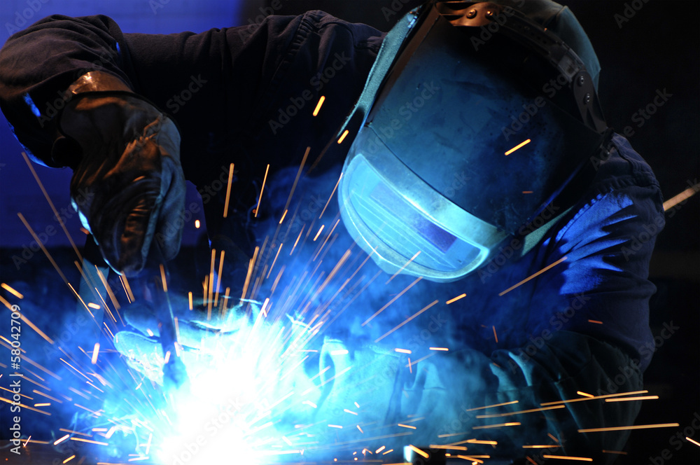 worker while doing a welding with arc welder - obrazy, fototapety, plakaty 