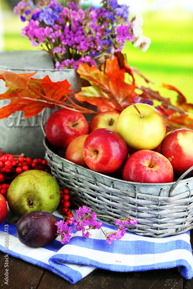 Juicy apples in basket on table on natural background