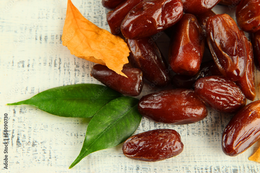 Dried dates with yellow leaves on wooden background