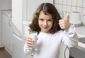 Little girl drinking milk in kitchen