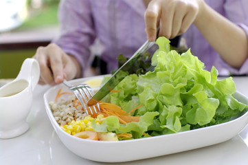 girl eating salad with knife and fork